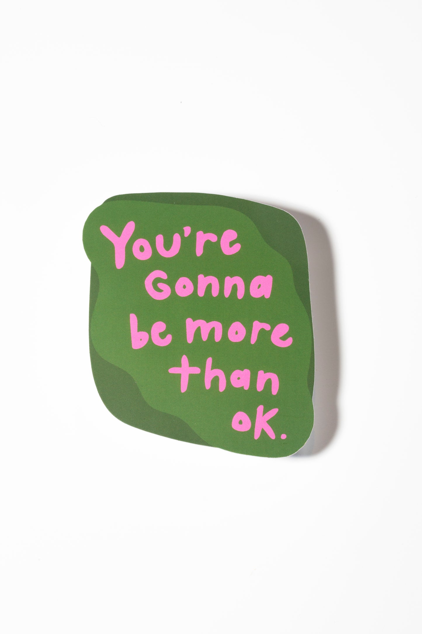 Green sticker that reads "you're gonna be more than ok" in pink on a white background.