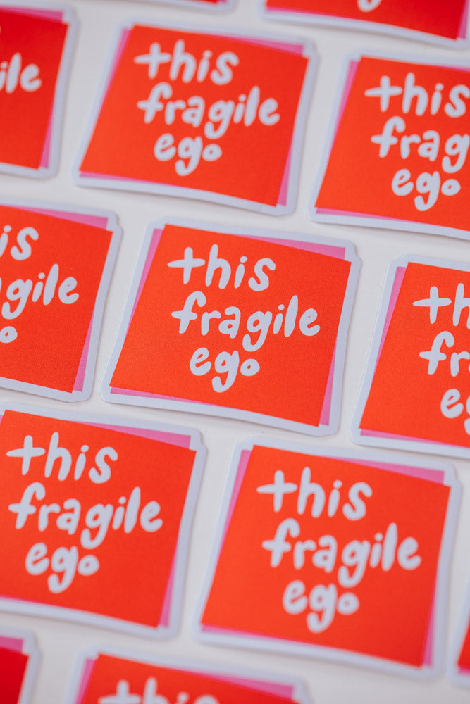 Multiple square stickers arranged in a grid pattern, each featuring white text reading 'this fragile ego' on a bright red background with pink border