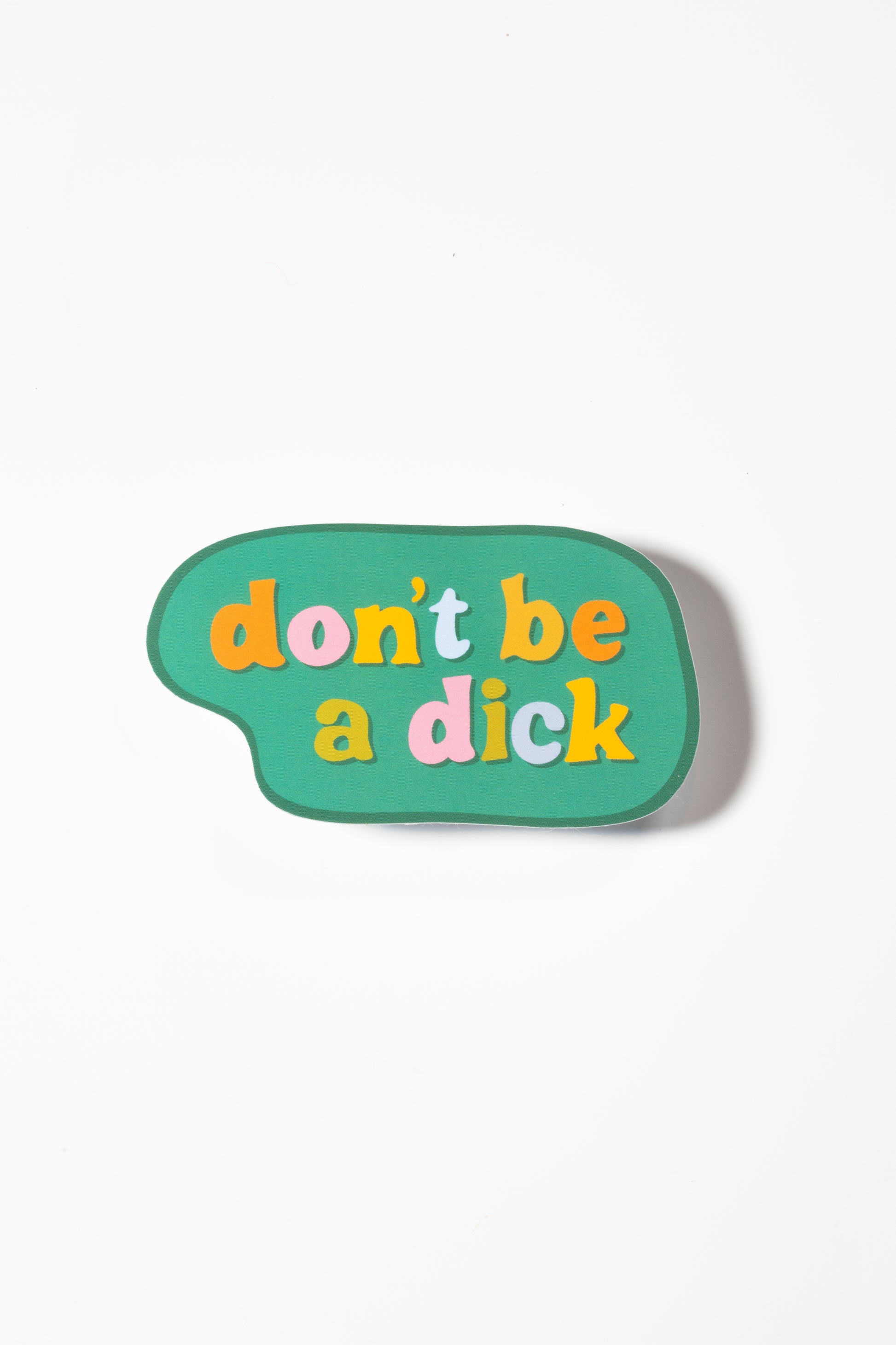 A speech bubble-shaped sticker on a white background featuring multicolored letters in orange, pink, and yellow spelling 'don't be a dick' on a sage green background