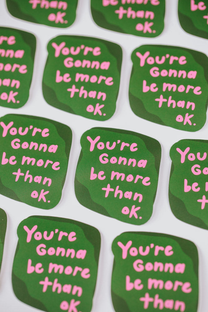 A motivational sticker featuring the phrase "You're gonna be more than okay," designed to inspire positivity and resilience.