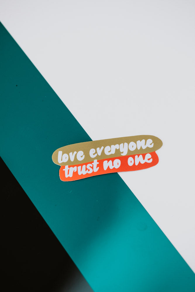 A green and white background with a gold and orange sticker featuring the text "love everyone trust no one" positioned in the lower right corner.