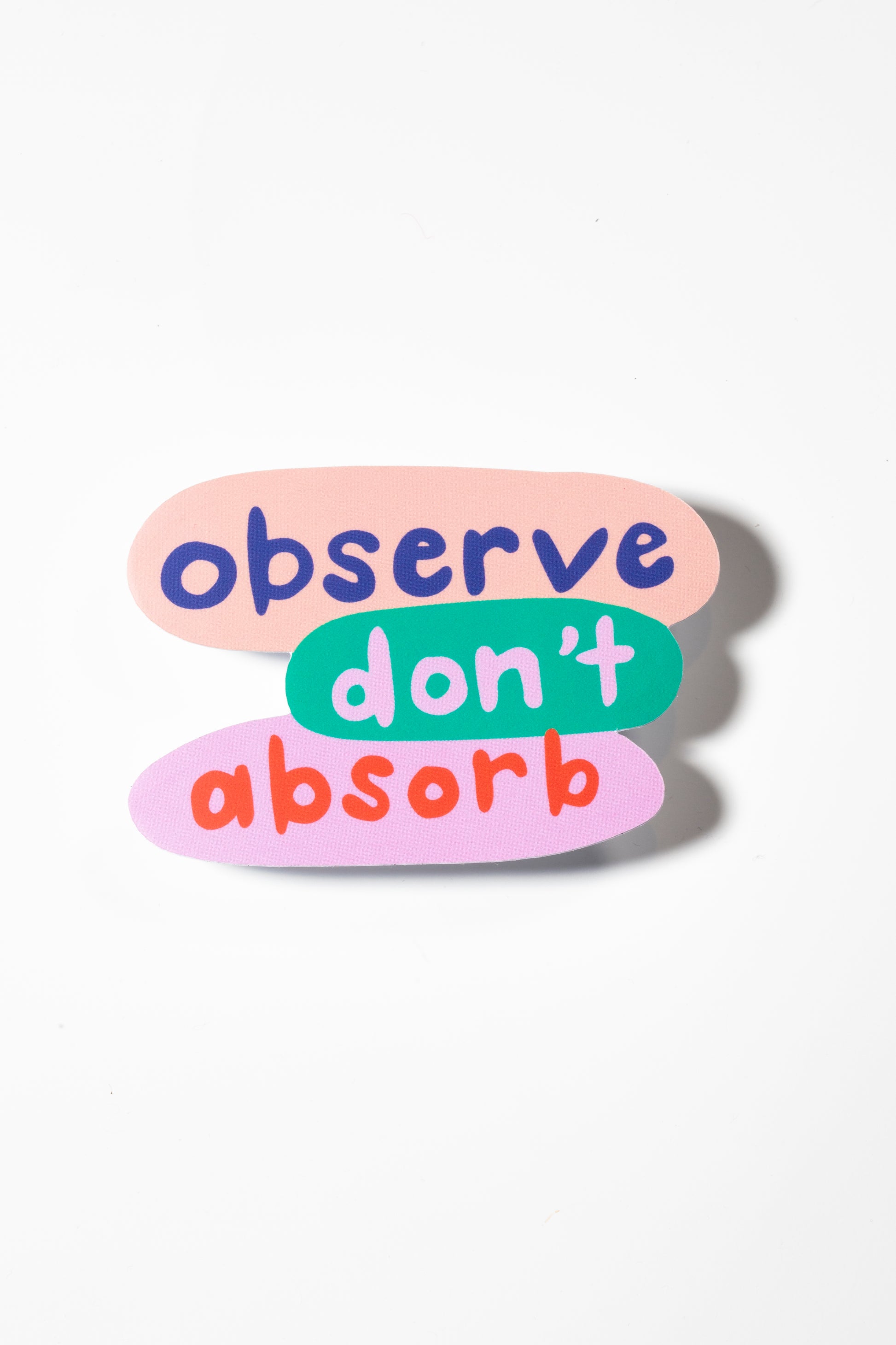 Sticker that reads "Observe Don't Absorb" in blue, lavender, and red all photographed on a white background.