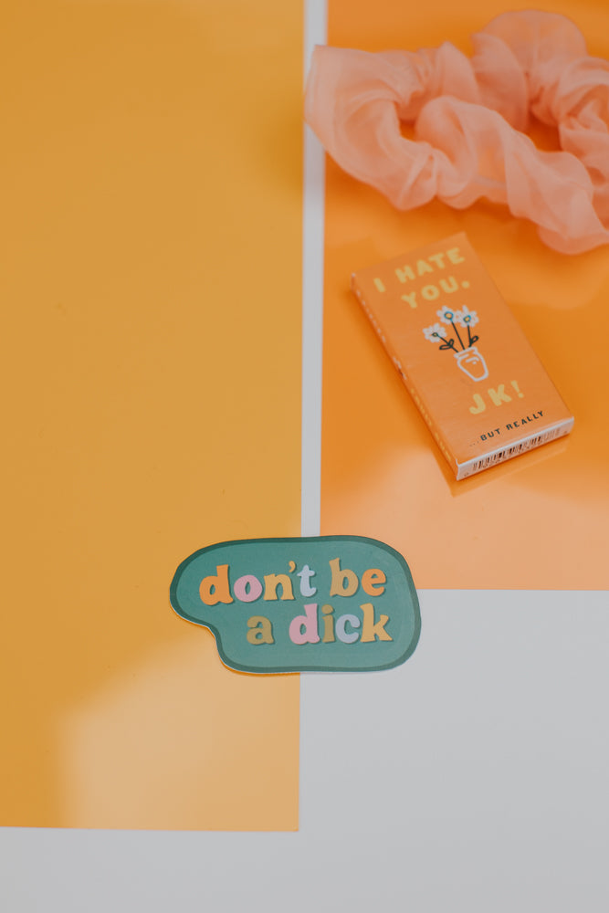 A sage green speech bubble sticker placed on a geometric background with sections of white, orange, and red colors