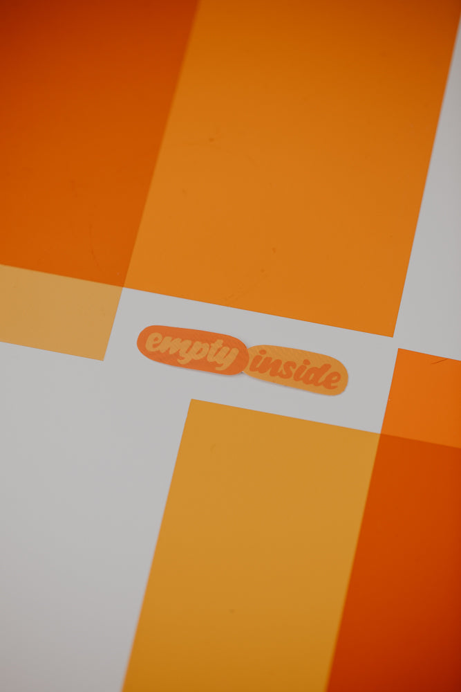 An image showing the text "empty inside" displayed in a bold, orange font against a bright orange and yellow geometric background.